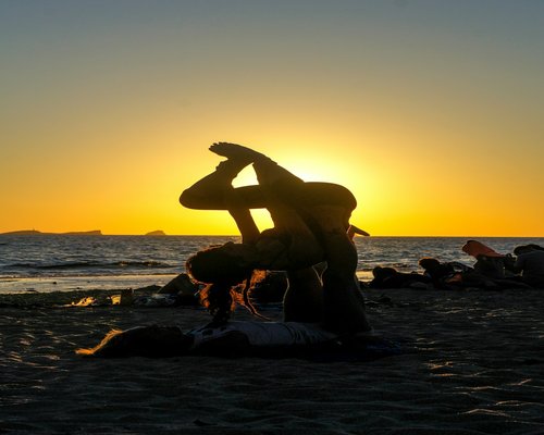 person doing gentle yoga stretches at sunset